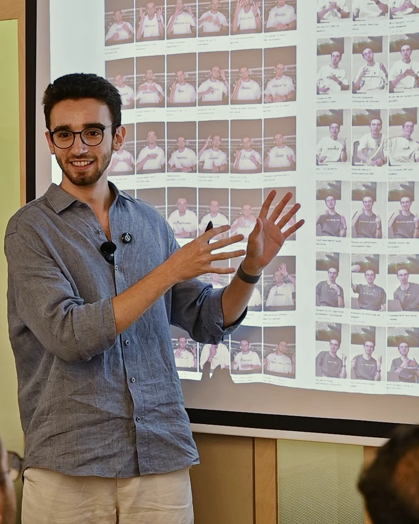 Grigory Tal on stage in Tel Aviv, pointing at a wall of his shorts on the screen behind him